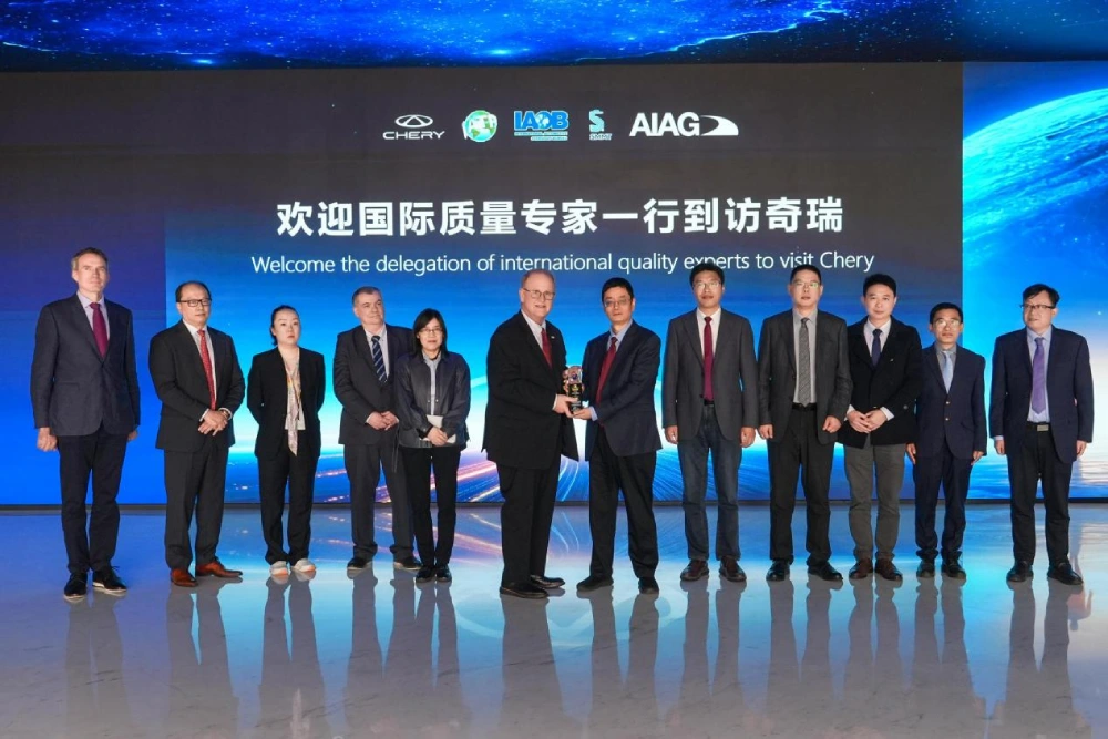 Chery Başkanı Yin Tongyue'nin "Otomotivde Disiplinli İnovasyon Ödülü" töreninde sahnede tebrikleri kabul ettiği ve el sıkıştığı anlar.